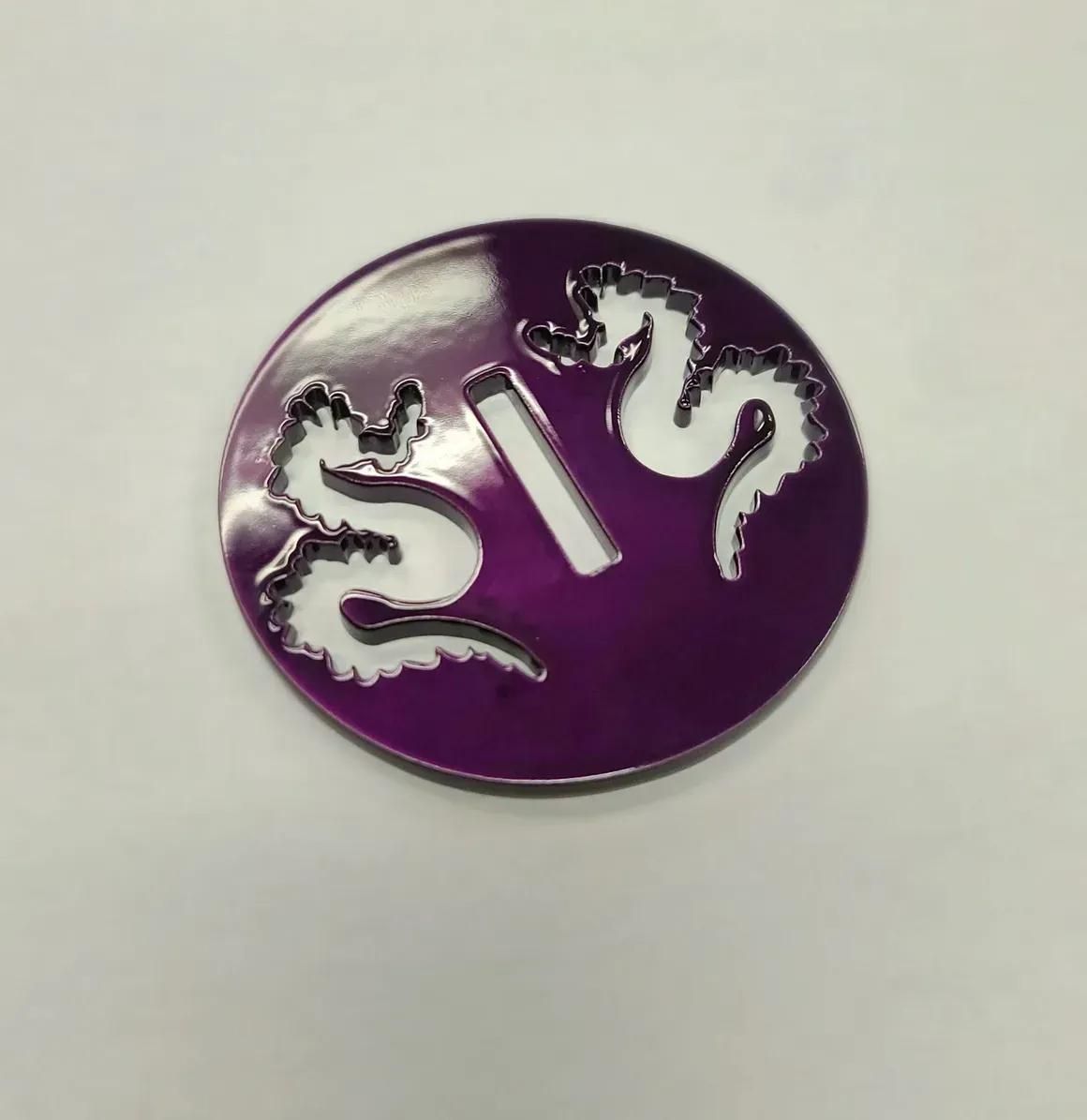 A circular purple object with a central vertical slot and cutouts shaped like two dragons facing each other.