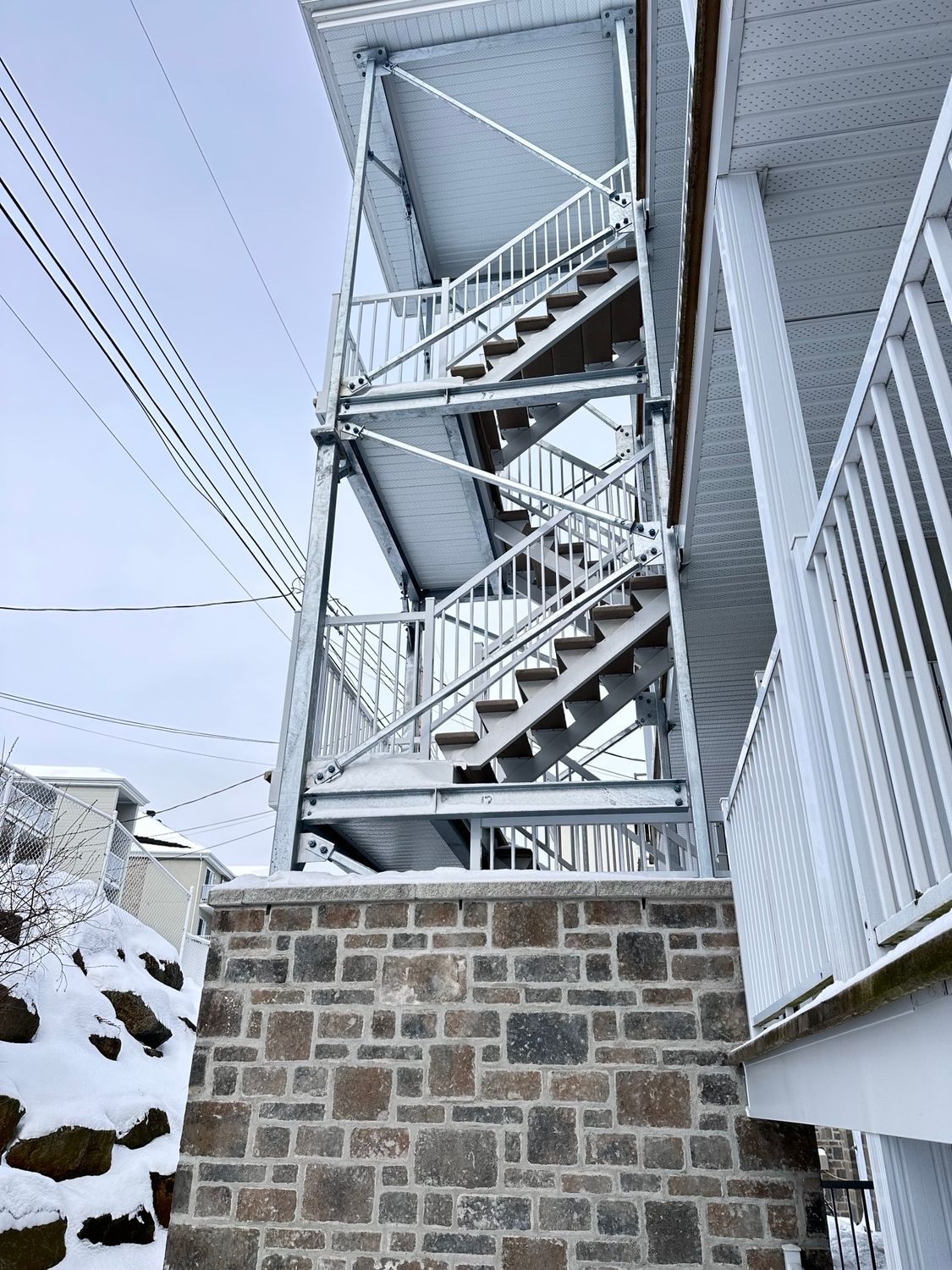 Un escalier de secours sur le côté d'un bâtiment à côté d'un mur de pierre.