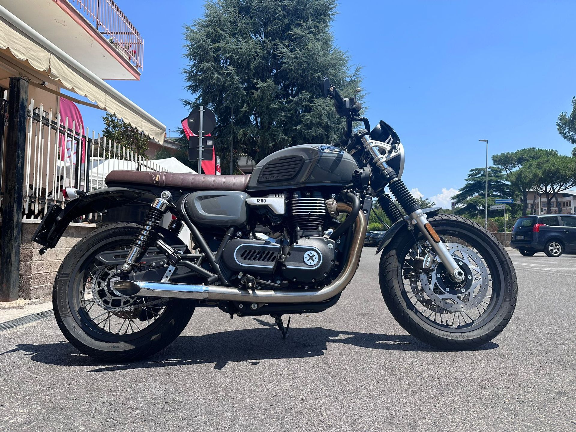 Una motocicletta nera parcheggiata in una strada soleggiata accanto a un edificio con panni stesi ad asciugare.