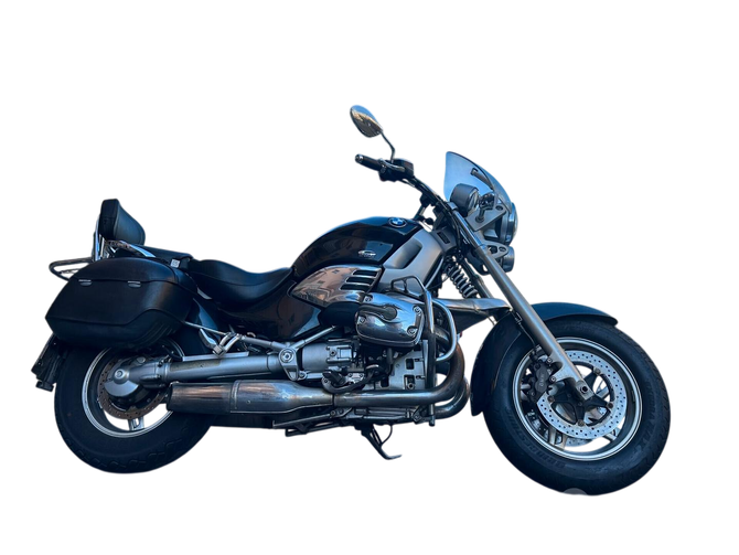 Moto da turismo nera con scarichi cromati, borse laterali e parabrezza, vista laterale su sfondo bianco