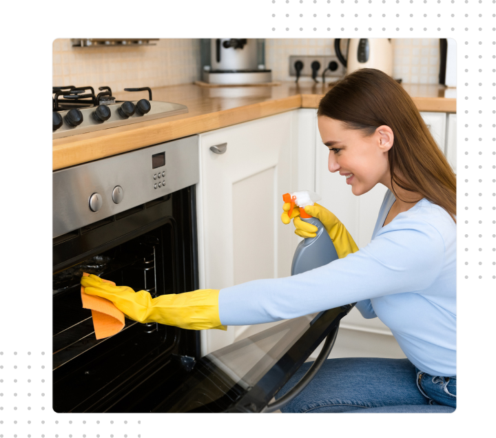 Woman in yellow gloves cleaning an oven with spray bottle in a modern kitchen