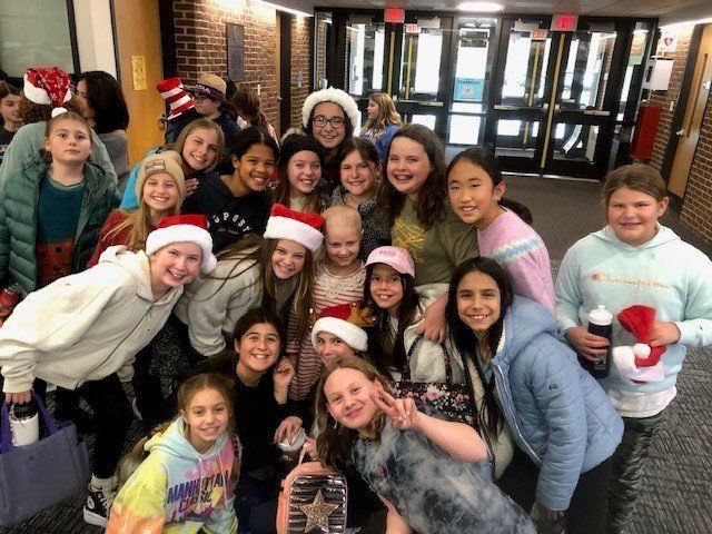 A group of young girls wearing santa hats are posing for a picture.
