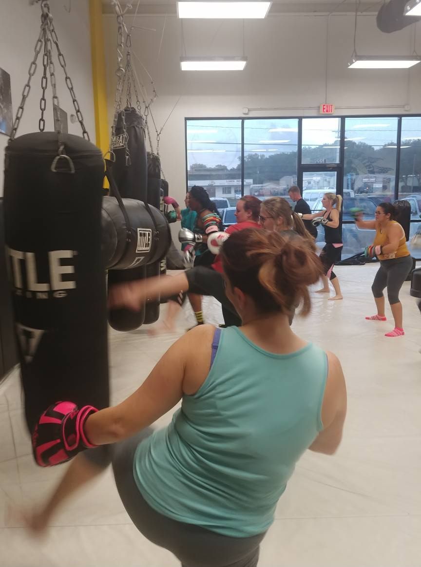 A woman is kicking a title boxing bag in a gym