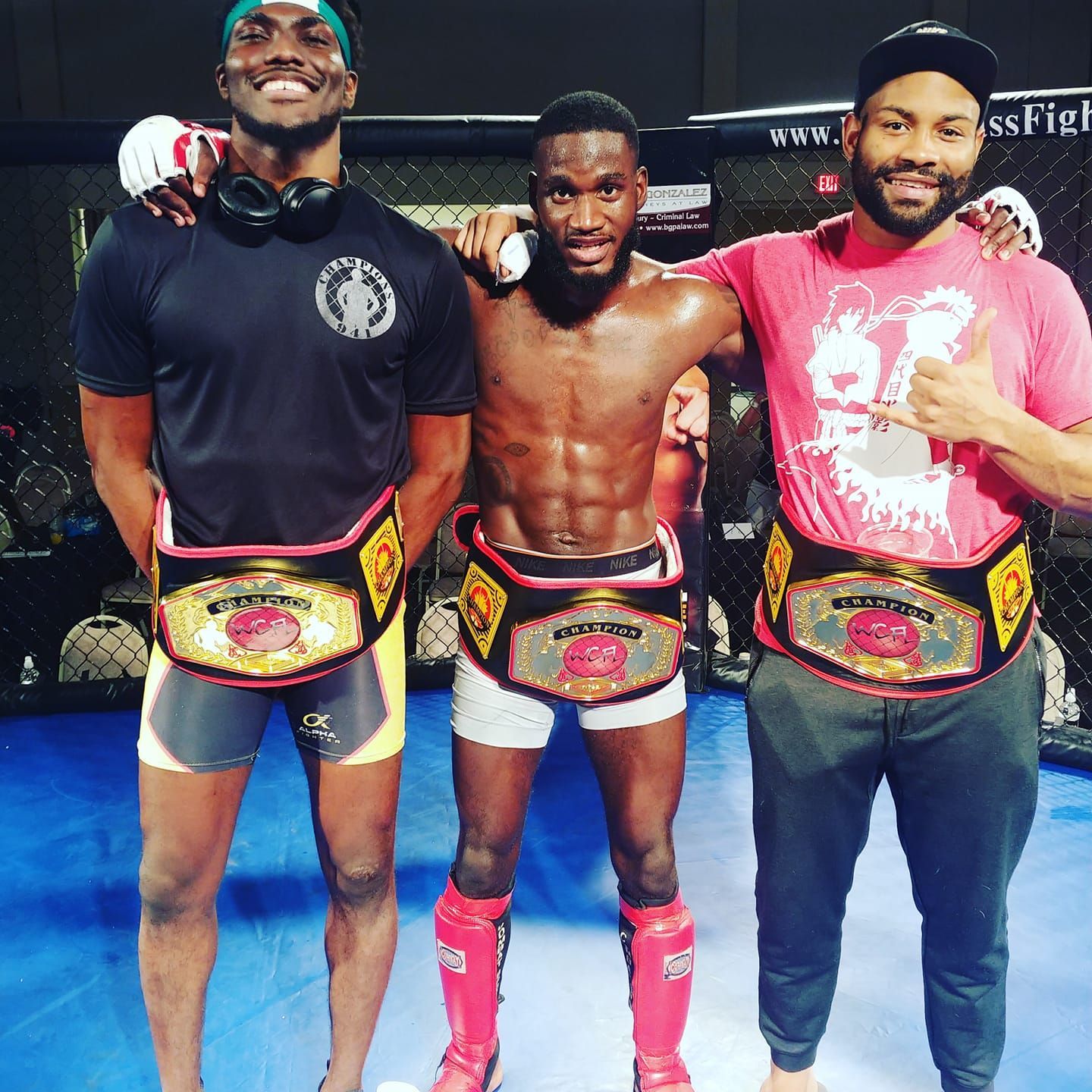 Three men posing for a picture with one wearing a shirt with the number 67 on it