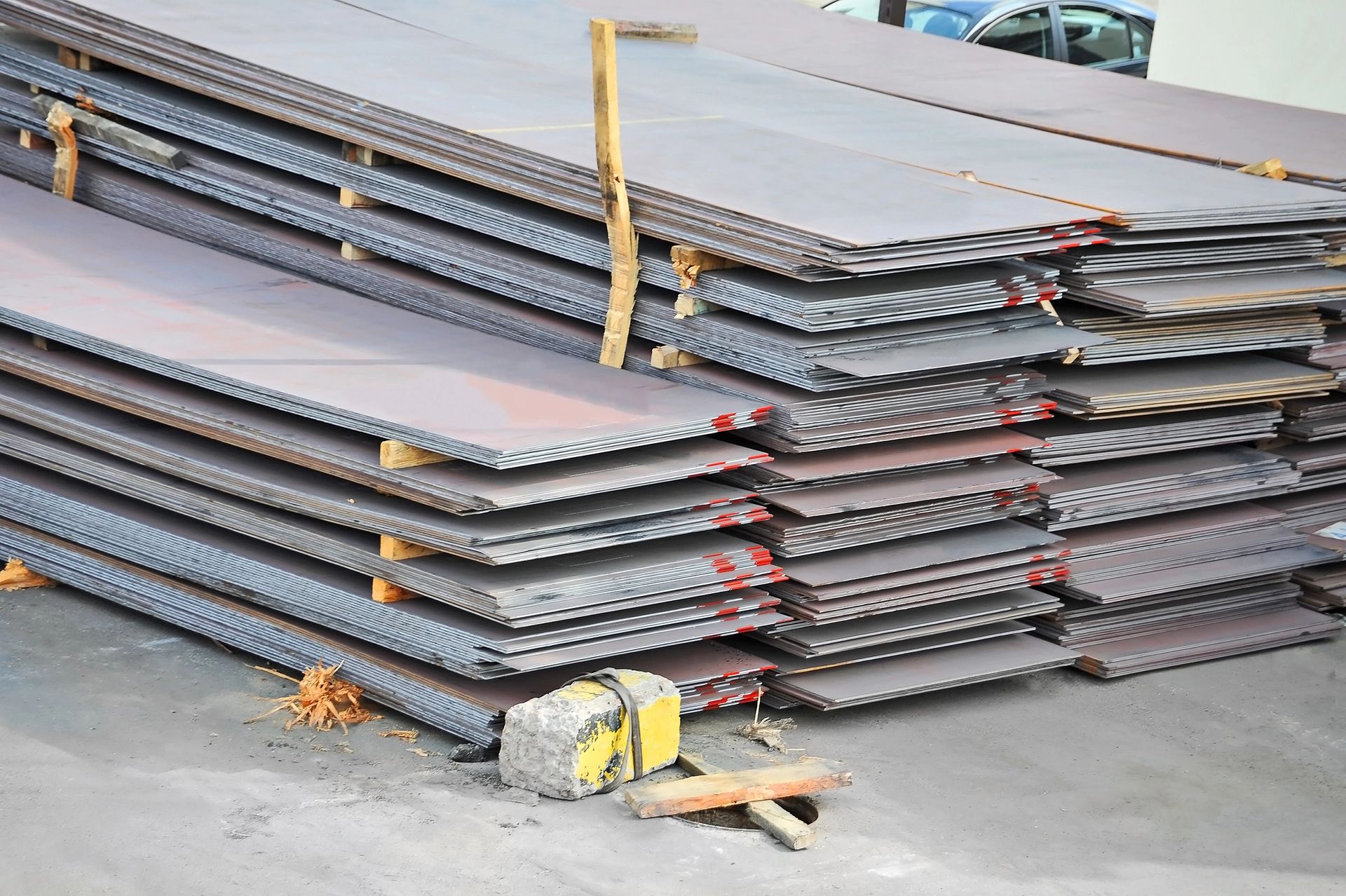 Pannelli metallici impilati e legati con cinghie sul pavimento di un magazzino.