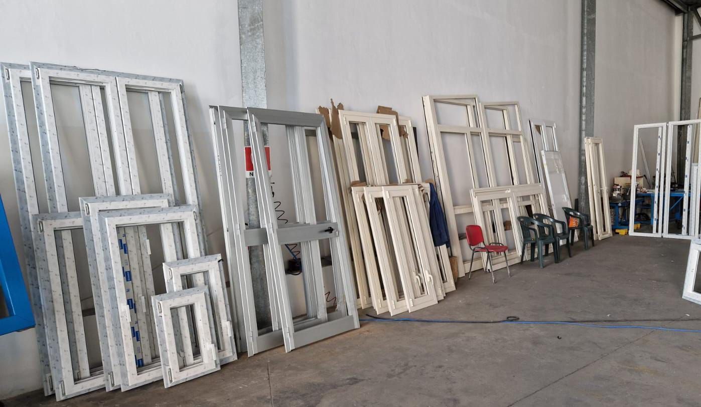 Pallet di metallo bianco impilati e appoggiati a un muro in una zona industriale.