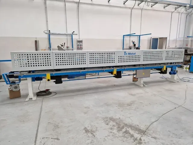 Grande macchinario industriale con copertura metallica perforata in un'officina luminosa.