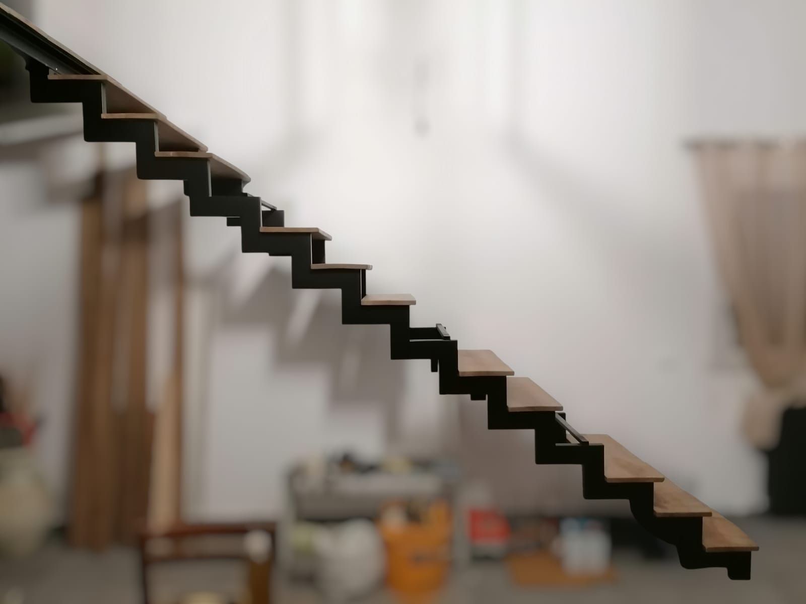 Scala sospesa con gradini scuri su uno sfondo interno sfocato