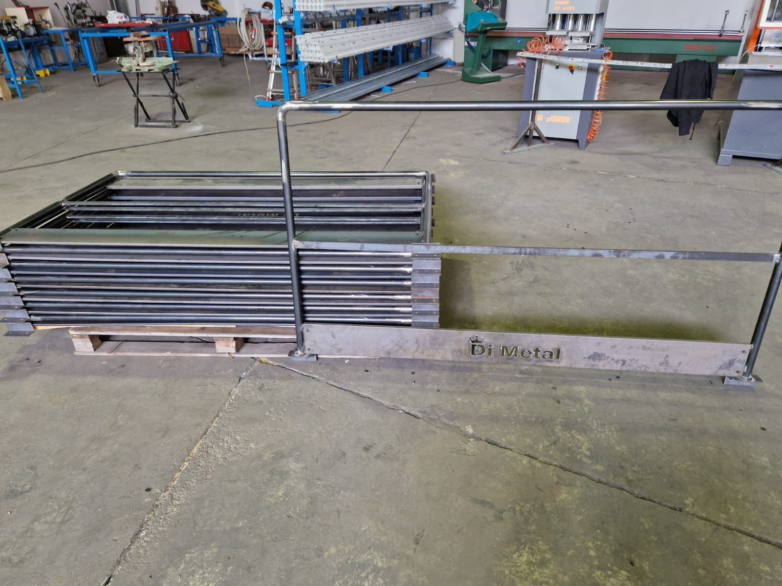 Telai metallici industriali impilati su un pallet in un'officina, con scaffalature blu sullo sfondo.