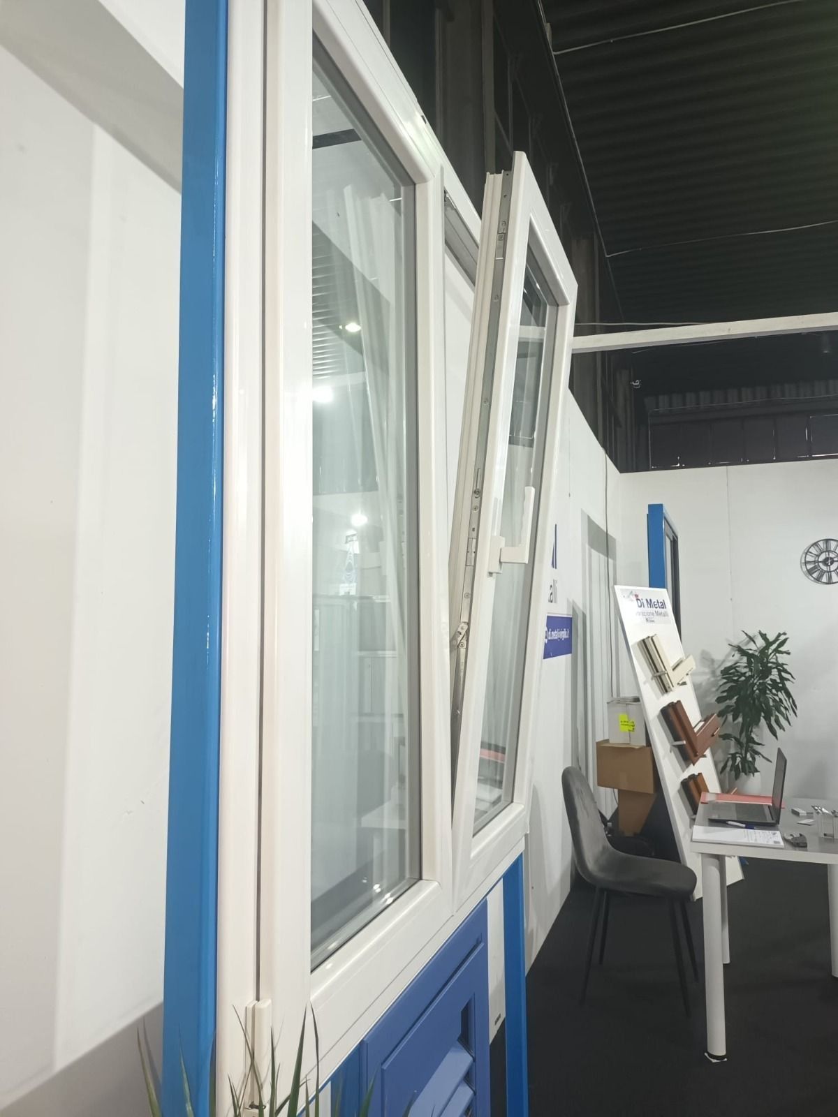 Finestre bianche e blu e un tavolino in un luminoso corridoio di uno showroom interno.