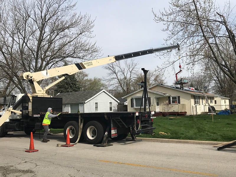 A truck with a crane attached to it is parked on the side of the road.