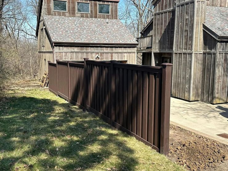Brown fence beside rustic wooden barns in a sunny rural yard