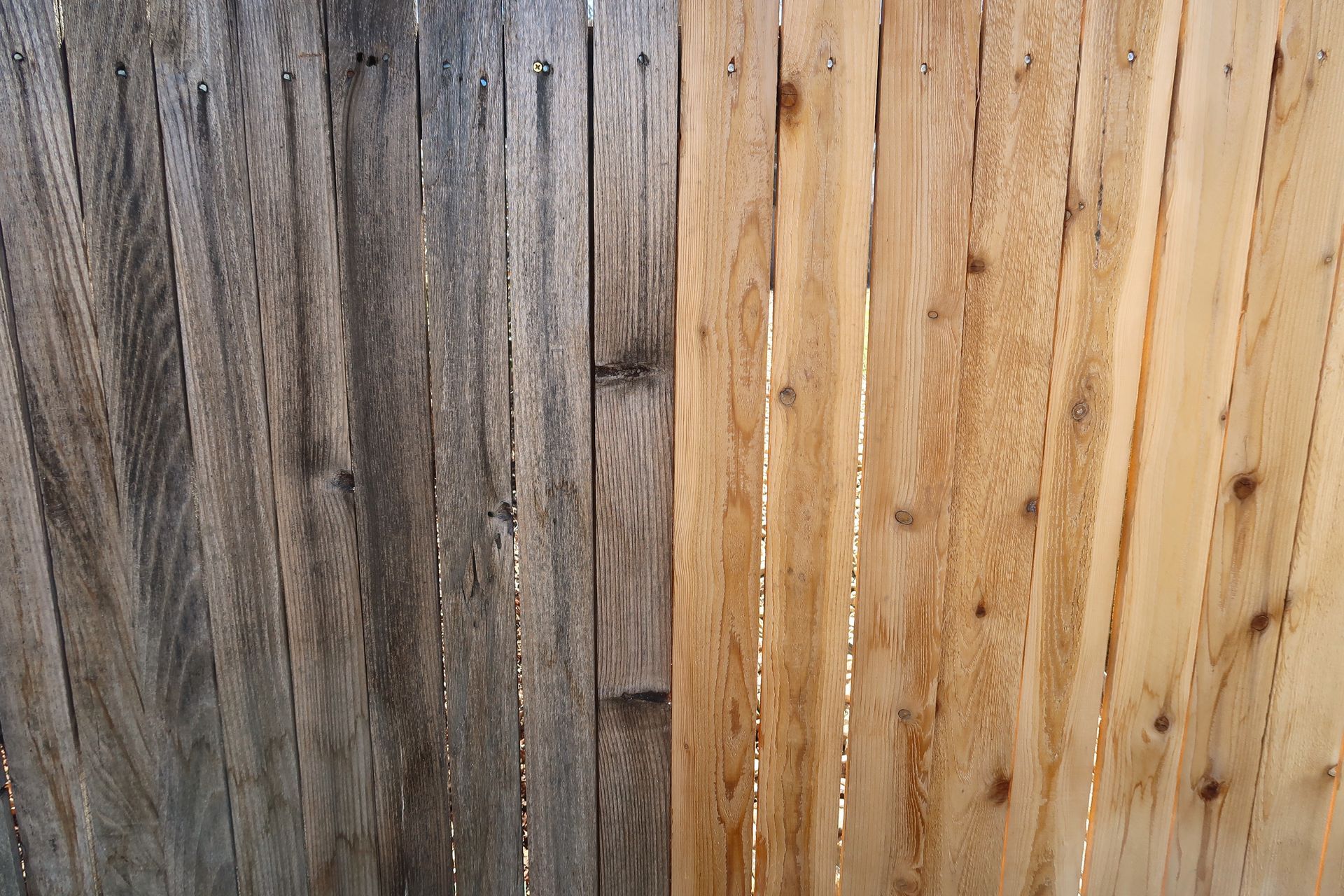 Vertical wooden fence boards in mixed gray and tan tones with visible knots and weathering