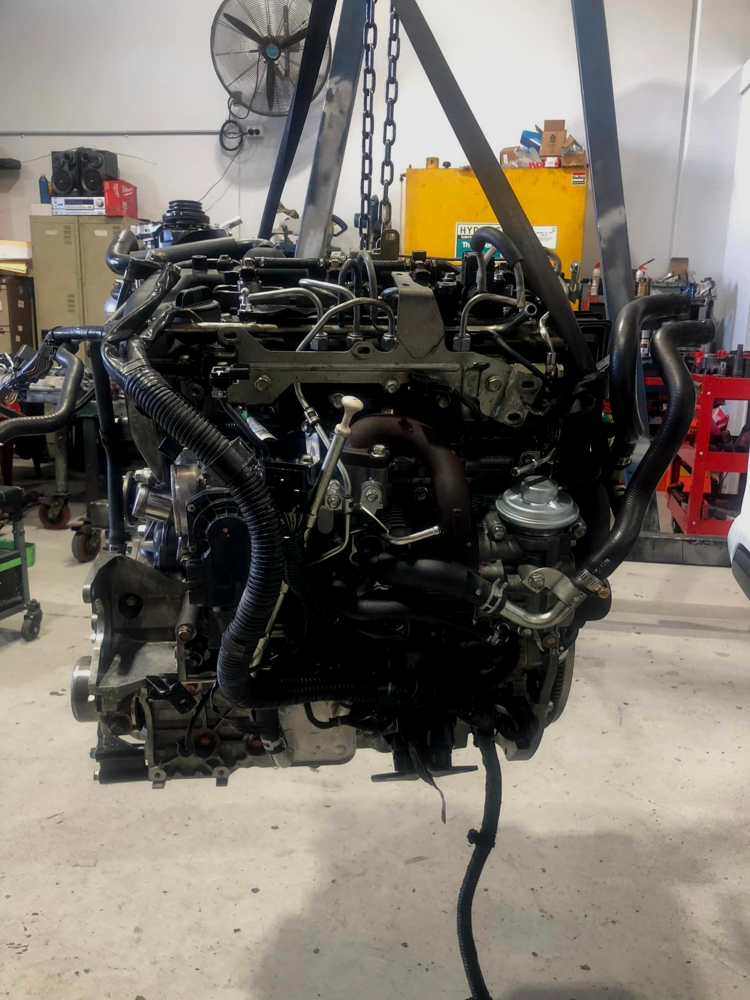 Engine suspended by a chain hoist in a workshop — Diesel Engine Rebuilding Australia in Gold Coast, QLD