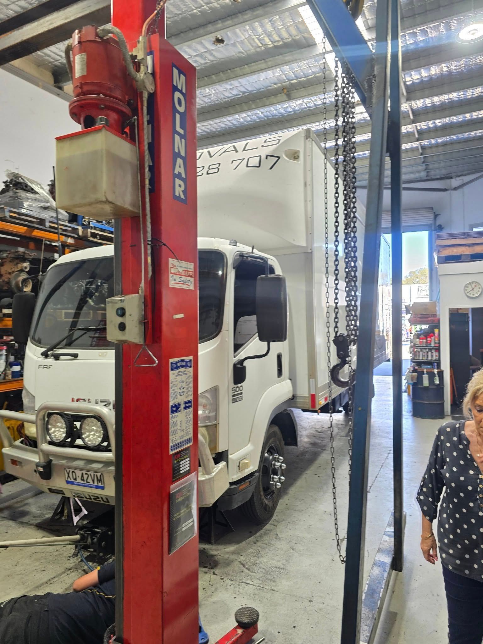 Red Molnar Lift Raising a White Truck in a Garage — Diesel Engine Rebuilding Australia in Gold Coast, QLD