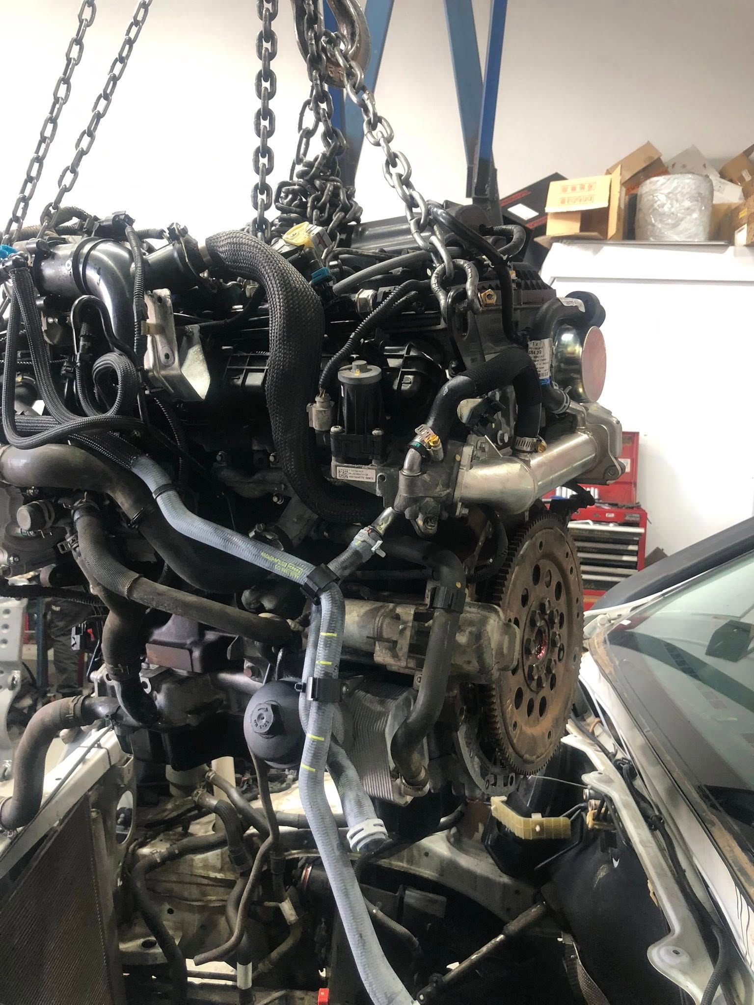 Engine Suspended By Chains, Being Lifted Out Of A Car In A Garage — Diesel Engine Rebuilding Australia in Gold Coast, QLD