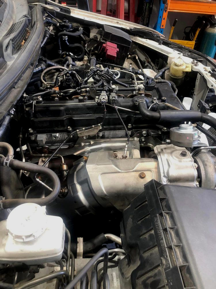 Car Engine Bay With Various Components  In A Repair Shop Setting — Diesel Engine Rebuilding Australia in Gold Coast, QLD