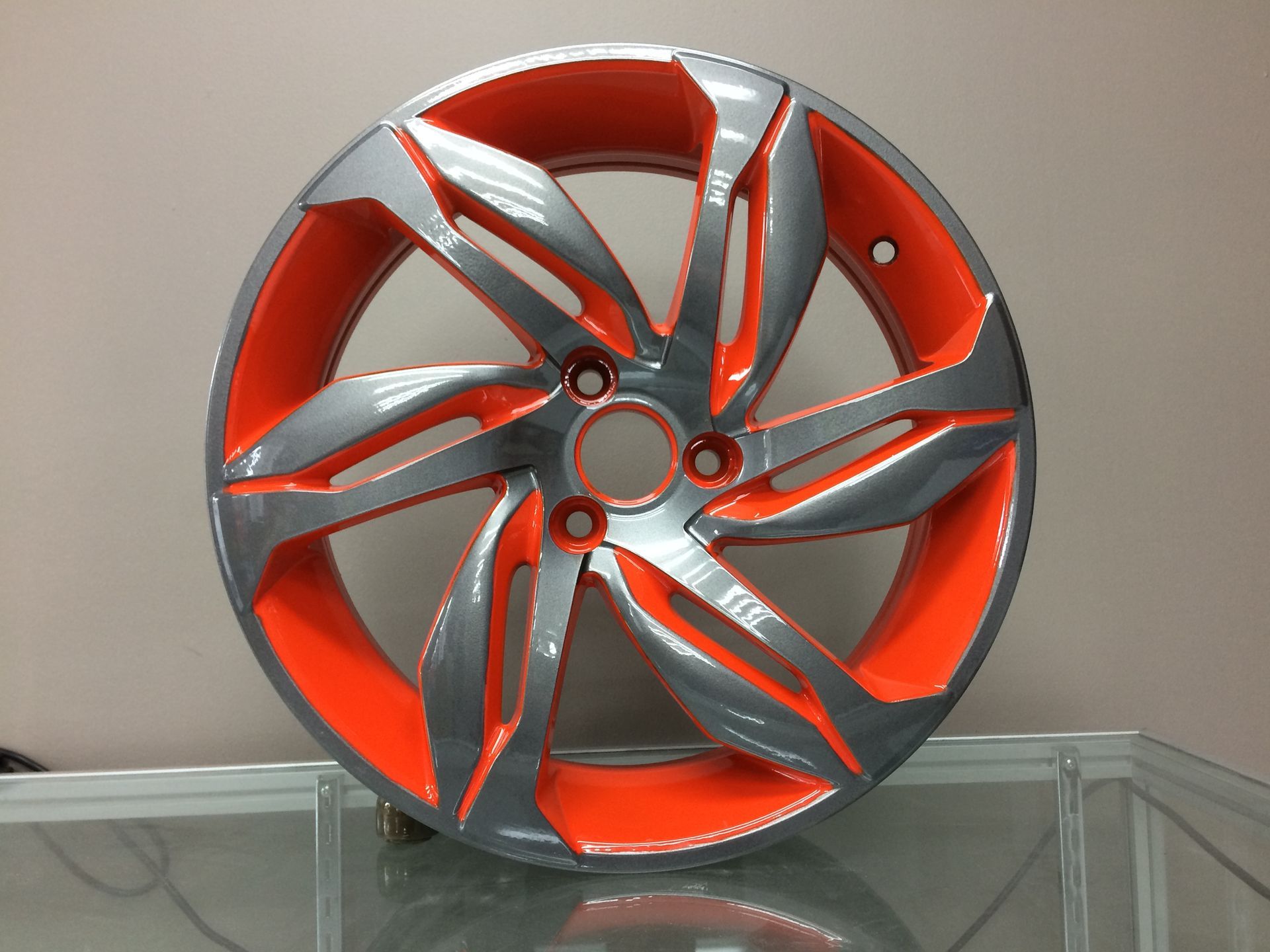 Une roue grise et orange repose sur une table en verre