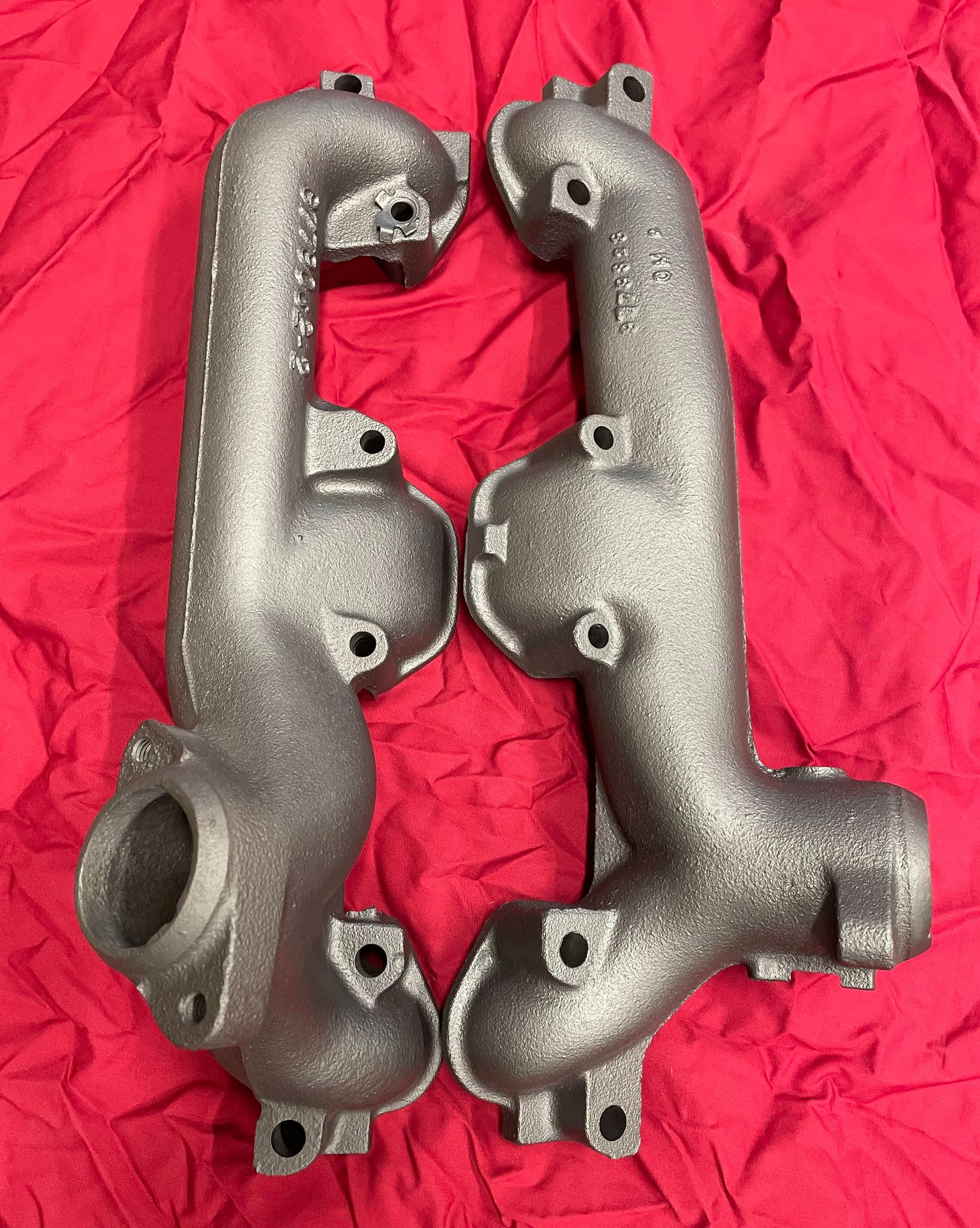 A pair of exhaust manifolds on a red cloth