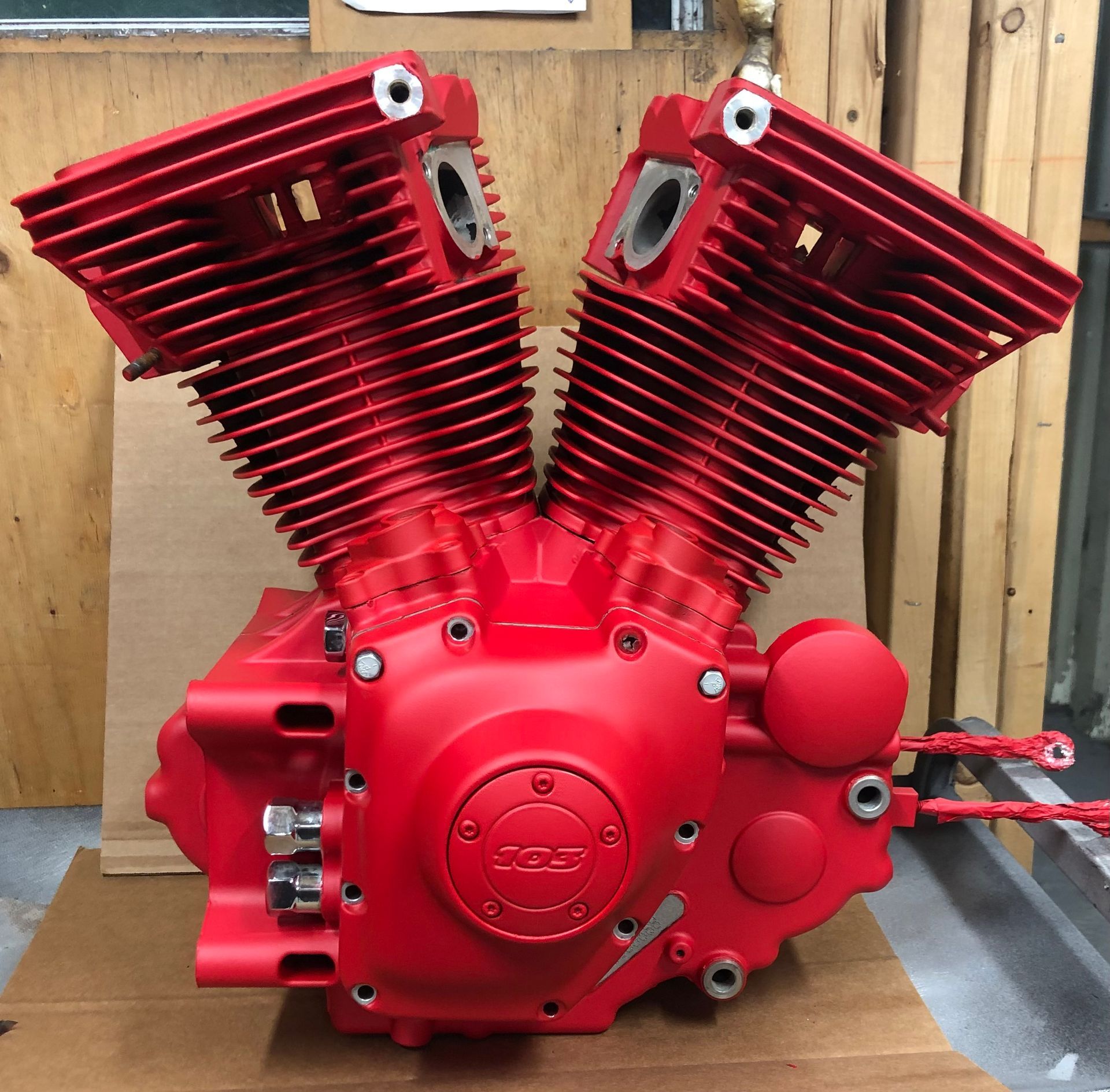 A red motorcycle engine is sitting on a cardboard box
