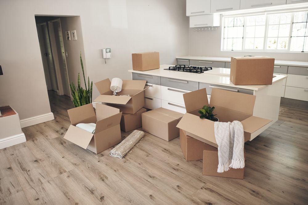 A kitchen with a lot of cardboard boxes on the floor.