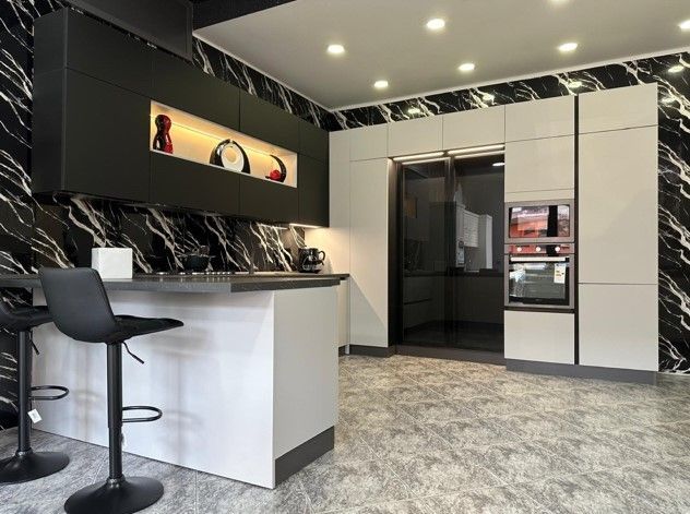 Una cucina con mobili bianchi e neri e pareti in marmo.