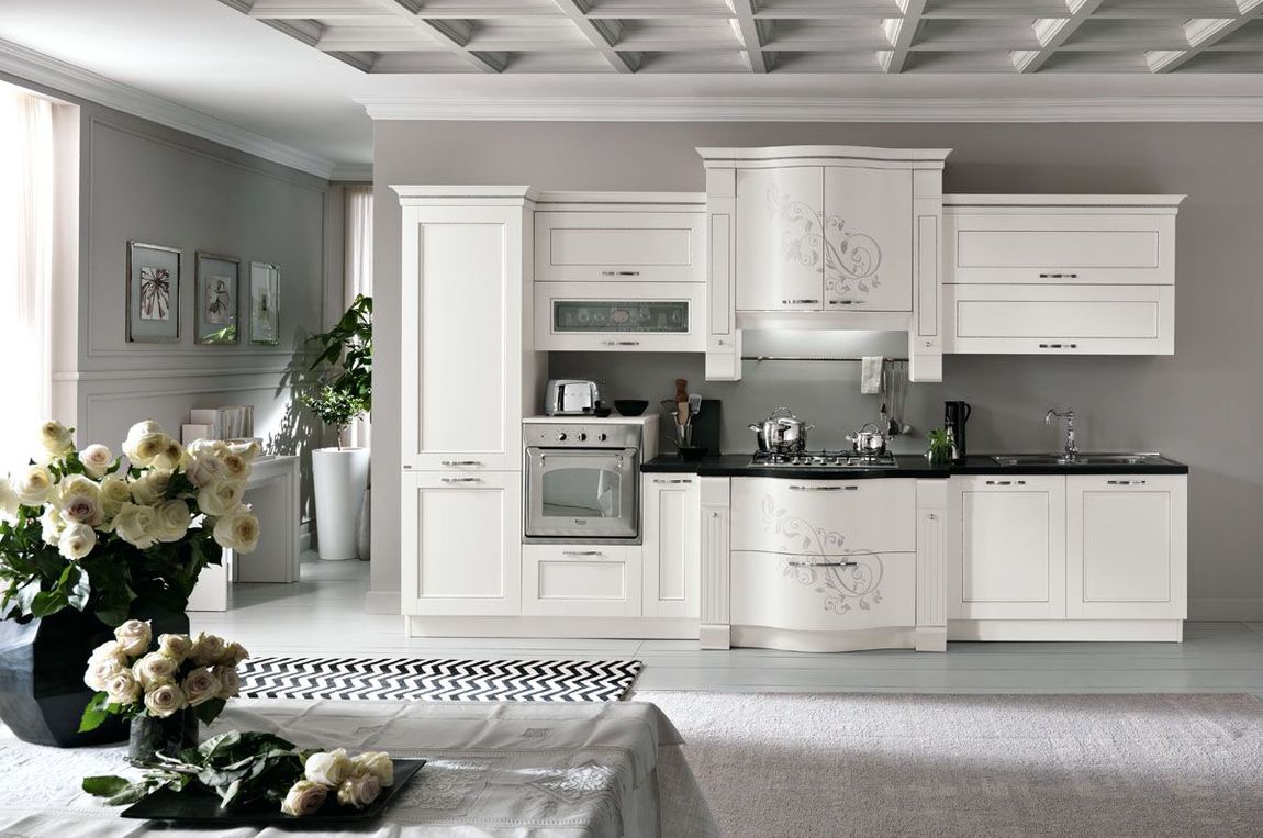 Una cucina con mobili bianchi e un piano di lavoro nero