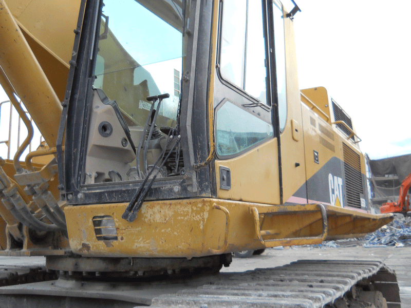 A yellow cat excavator is parked in a dirt lot