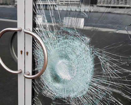 A close up of a broken glass door with a hole in it