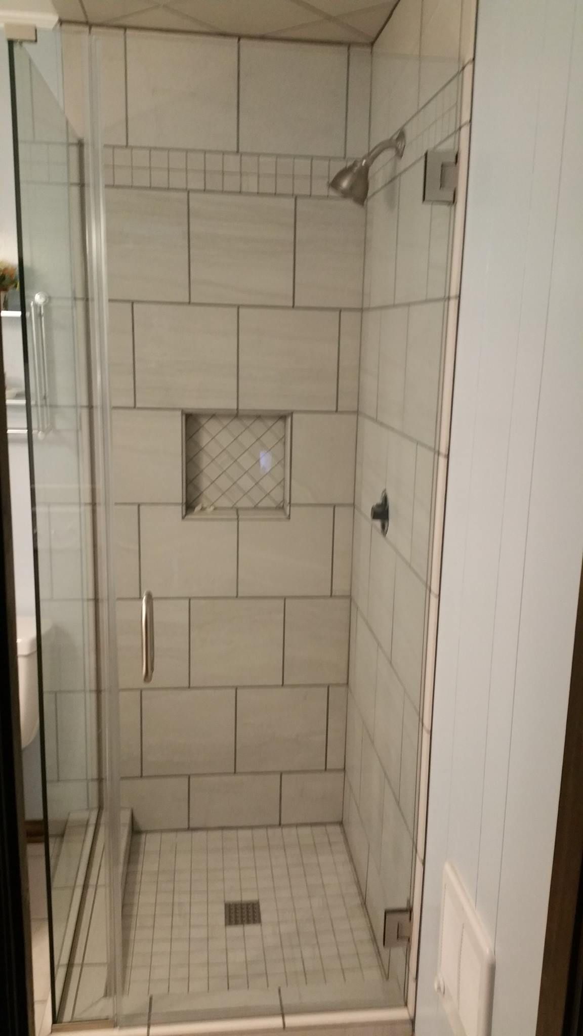 A bathroom with a walk in shower with white tiles and a glass door