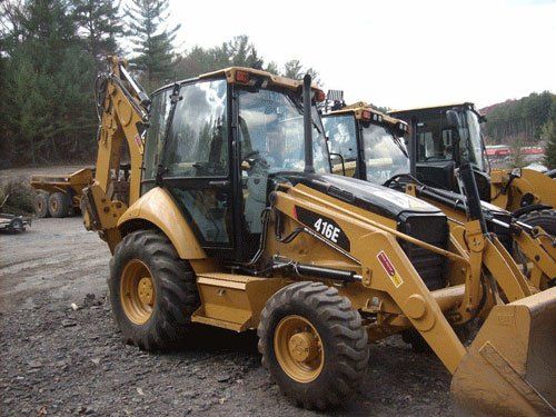 Two backhoe loaders are parked next to each other in a dirt lot