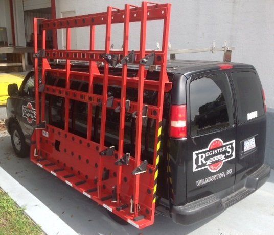 A black van with a red rack on the back is parked in front of a building