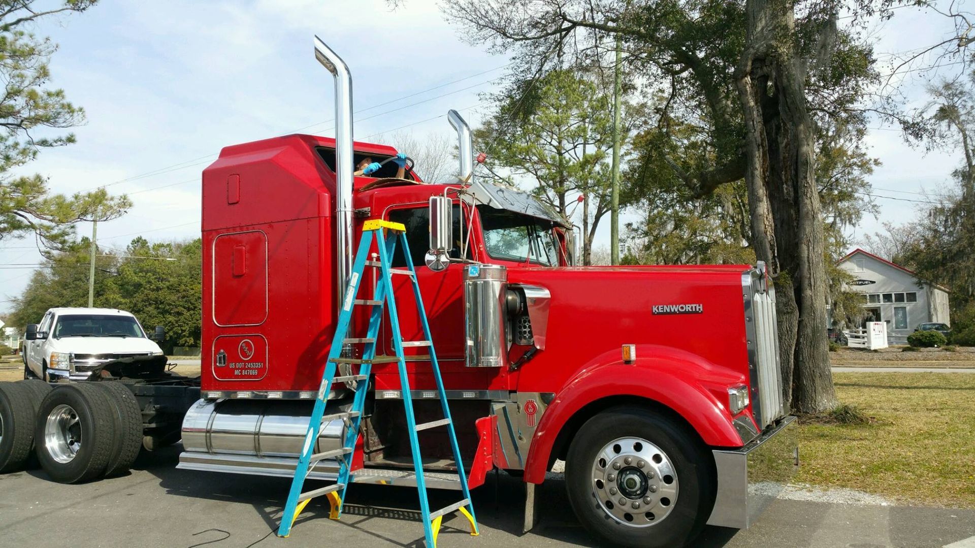 A red semi truck with a ladder attached to the side of it