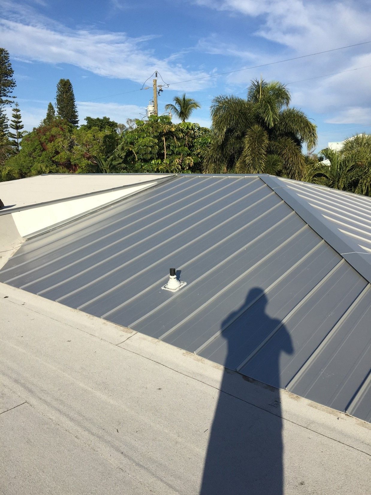 A shadow of a person is cast on the roof of a building — Tampa, FL — Bill Shields Roofing