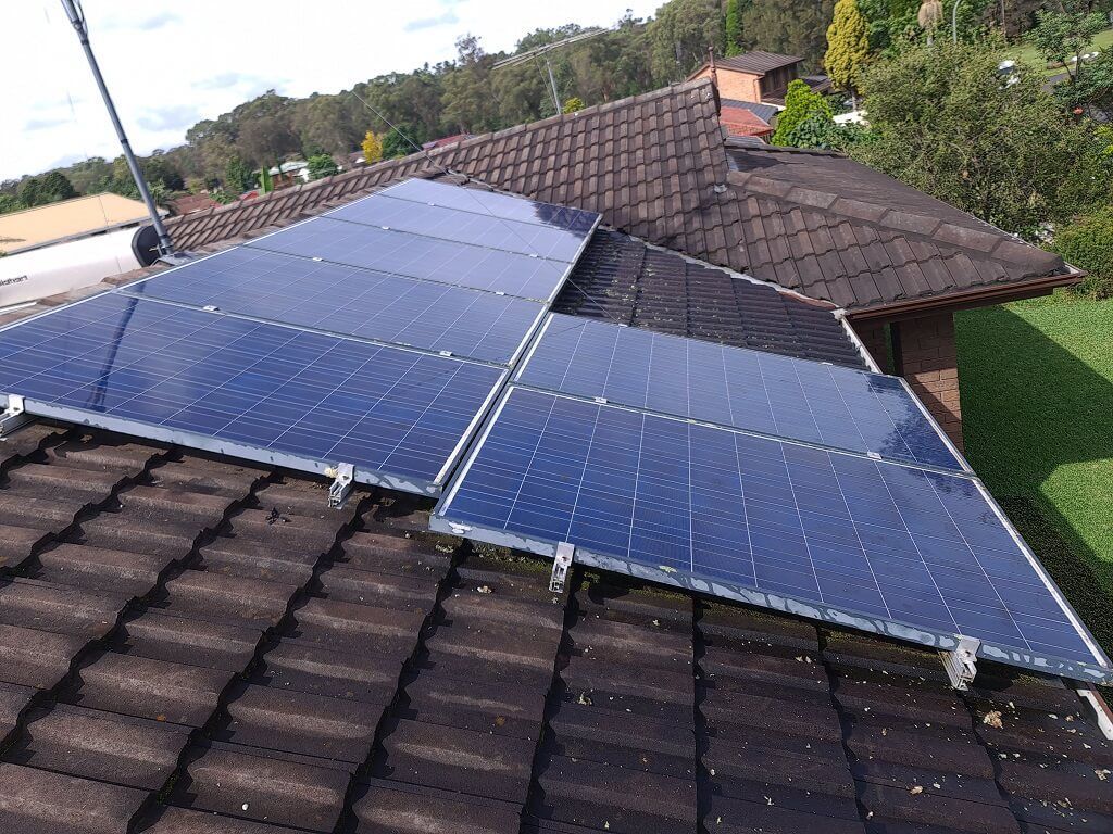 Solar panels installed on a brown tiled roof, in a residential setting.