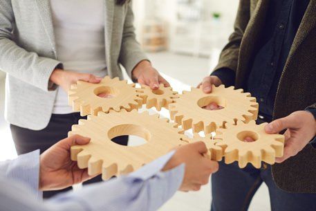 group of people holding wooden gears