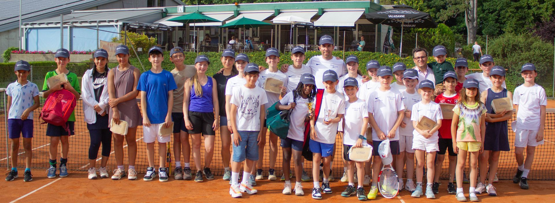 Un groupe d'enfants pose pour une photo sur un court de tennis