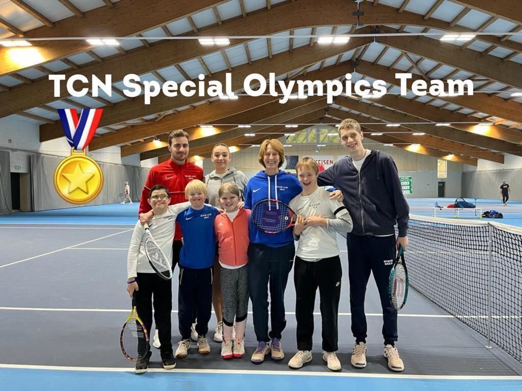 Un groupe de personnes pose pour une photo sur un court de tennis.