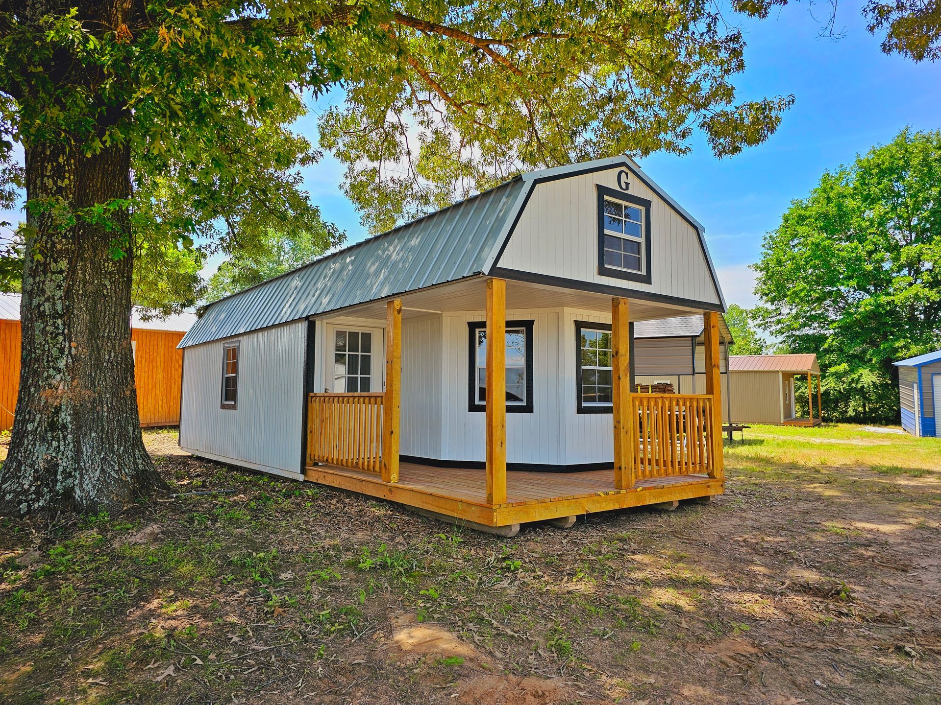 A small white house with a porch and a tree in the background.