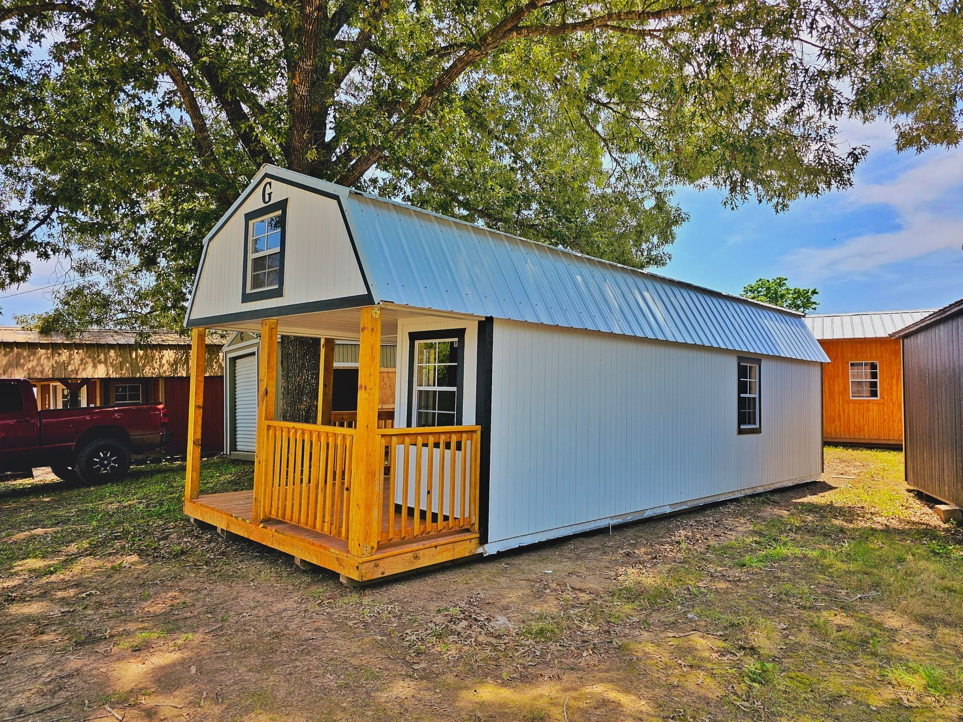 A small white house with a porch and a wooden deck.