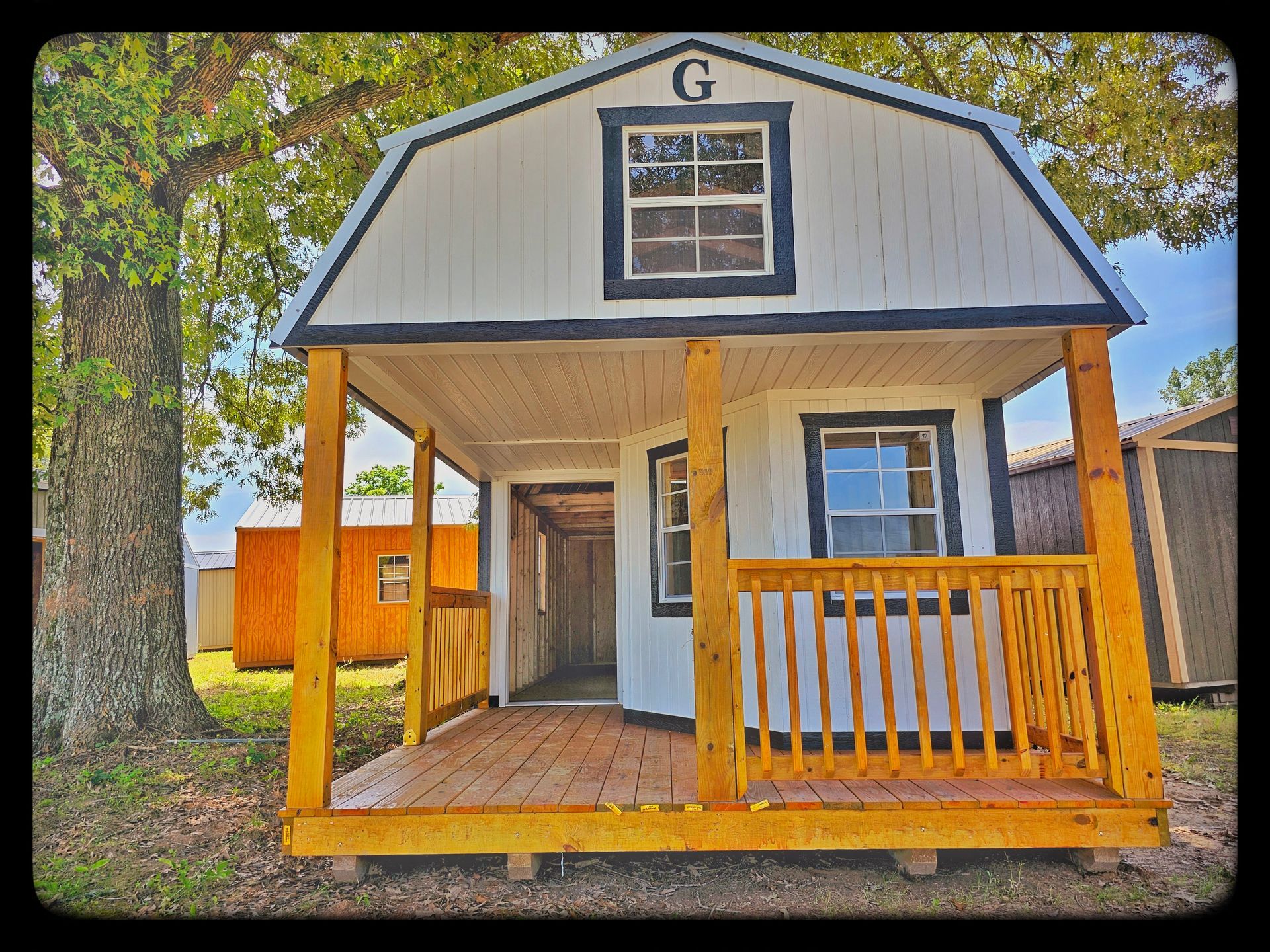 A small house with a porch and a g on the top of it