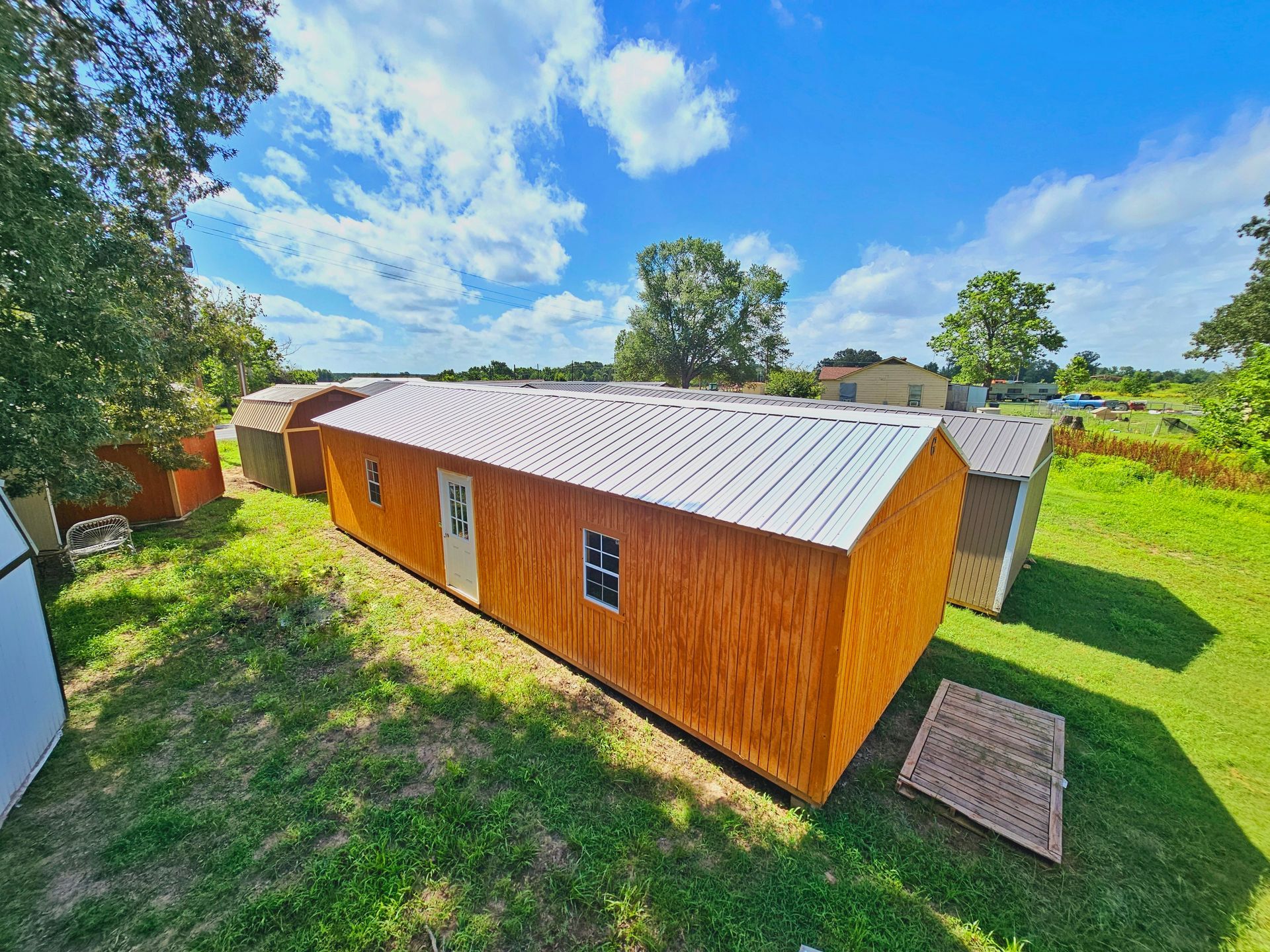A row of wooden sheds are sitting on top of a lush green field.