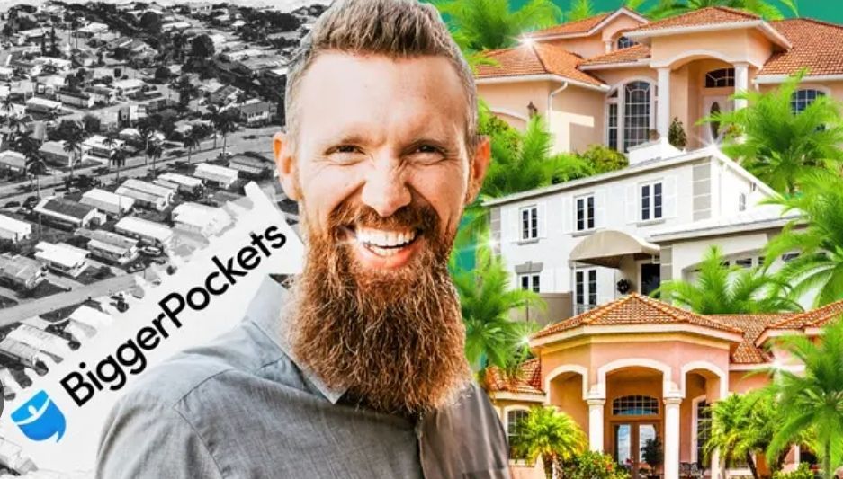A man with a beard is smiling in front of a large house.
