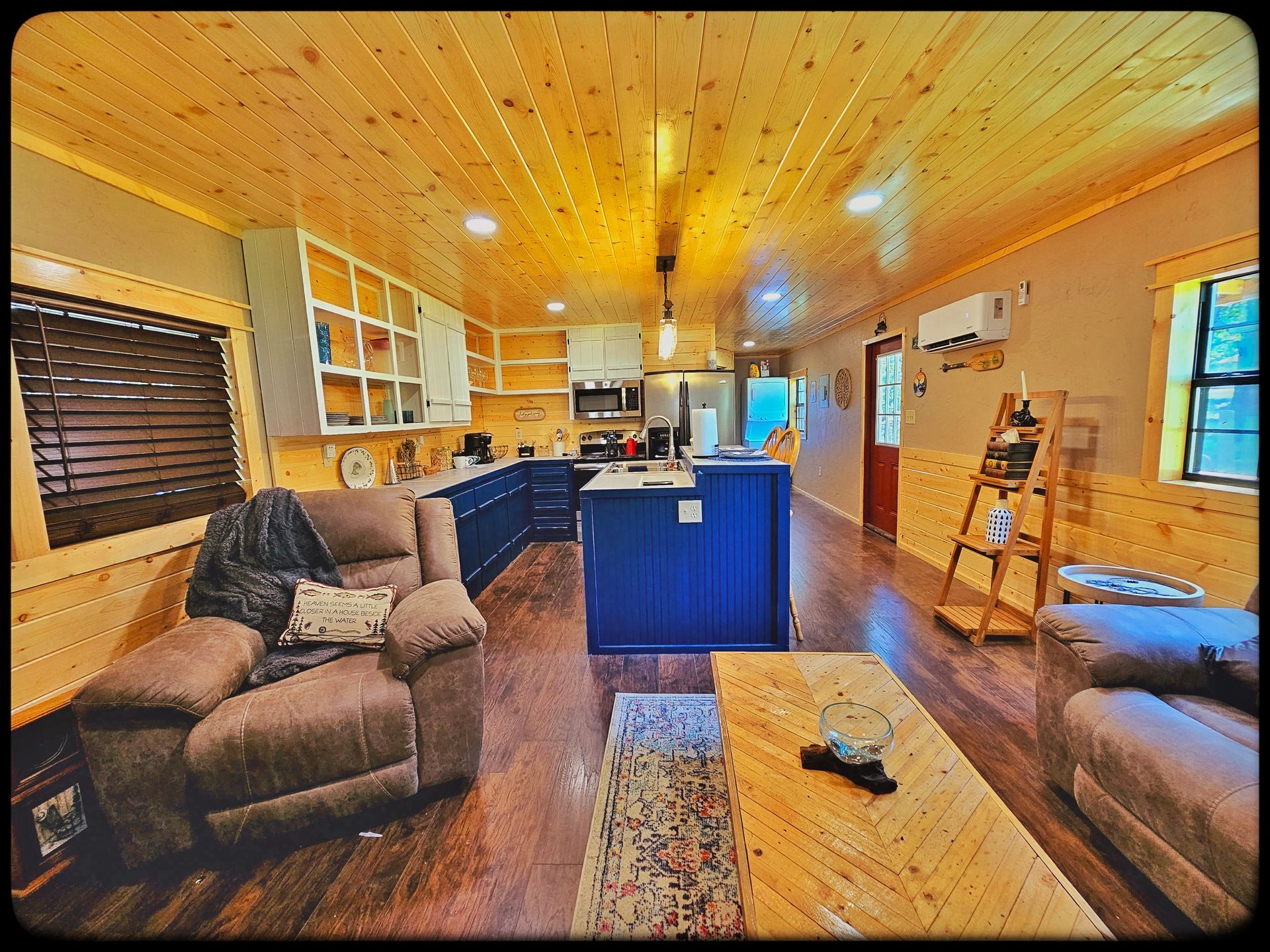 A living room with a couch , chair , coffee table and kitchen.