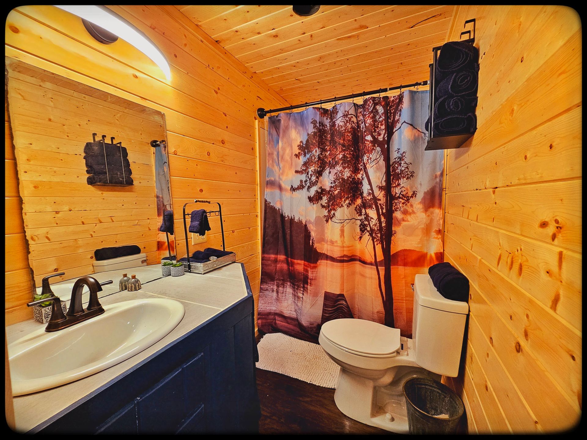 A bathroom with a toilet , sink , mirror and shower curtain.