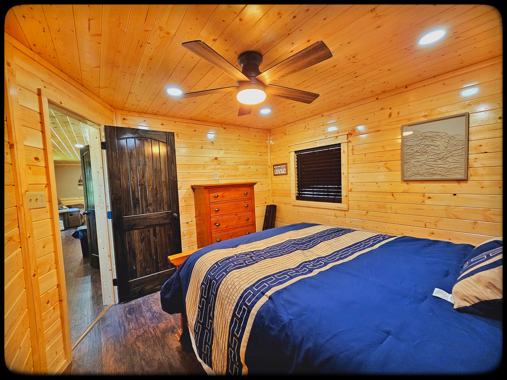 A bedroom with a bed , dresser , and ceiling fan.