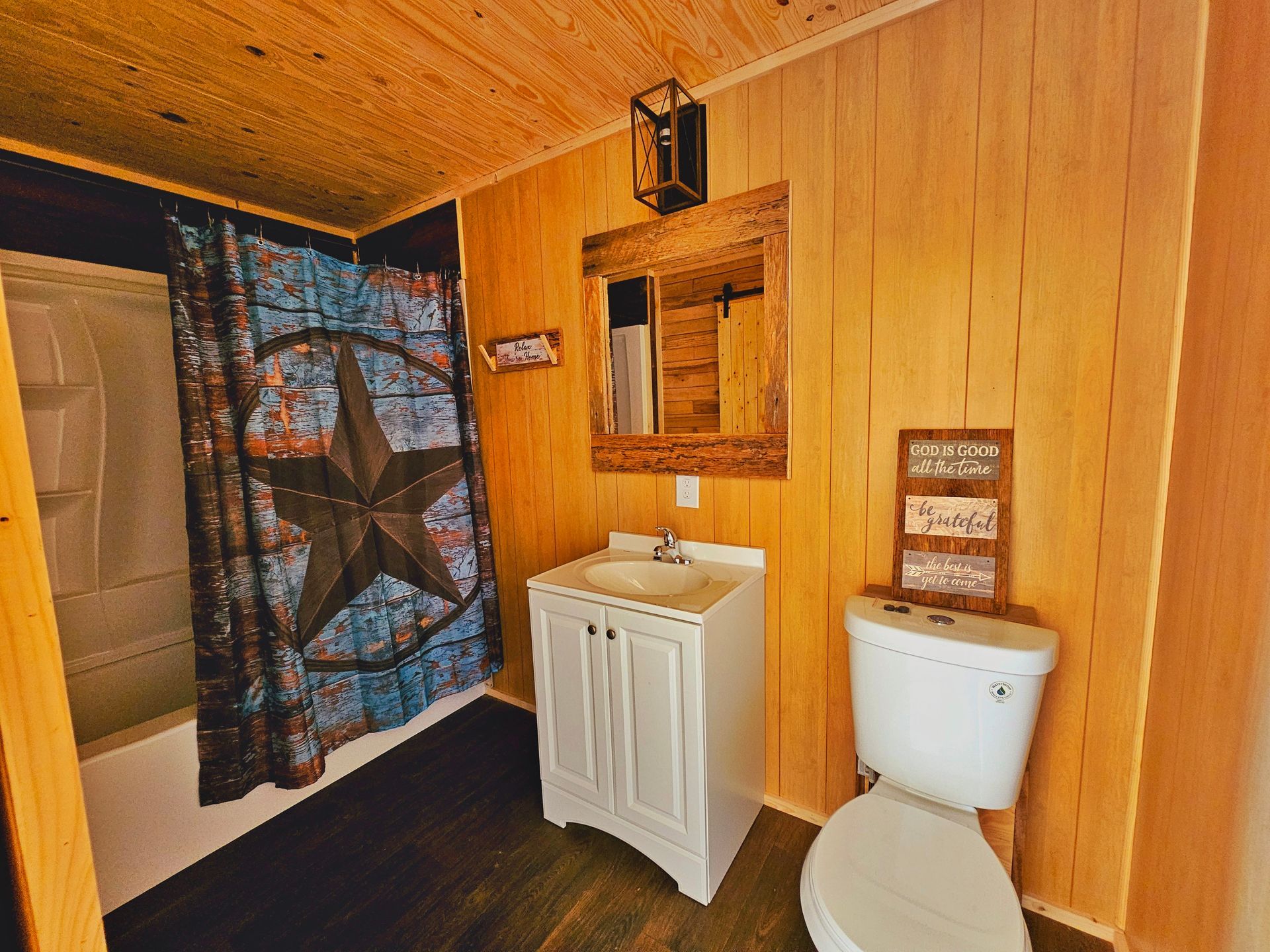 A bathroom with a toilet , sink , shower and mirror.