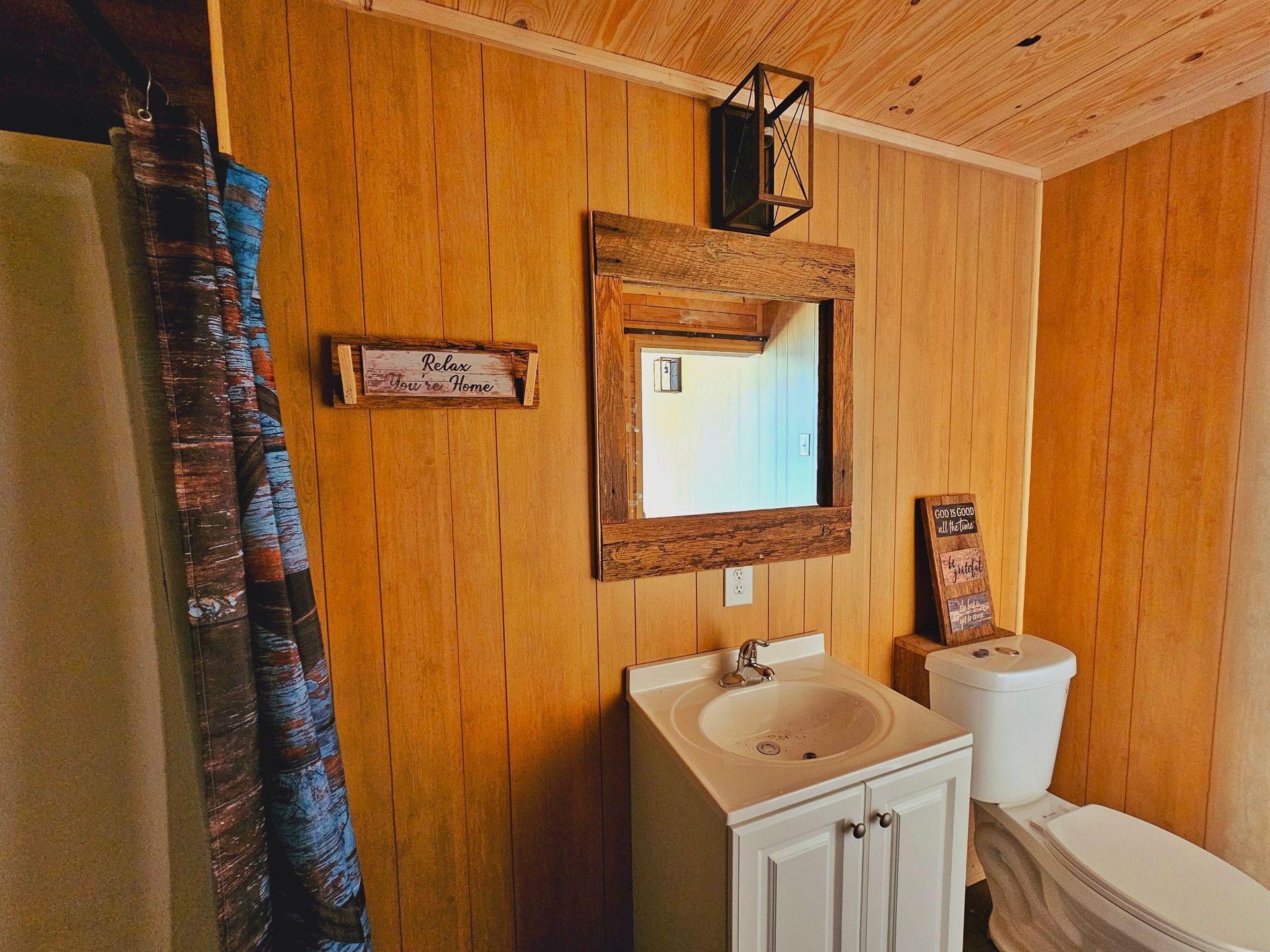 A bathroom with a sink , toilet , mirror and shower curtain.