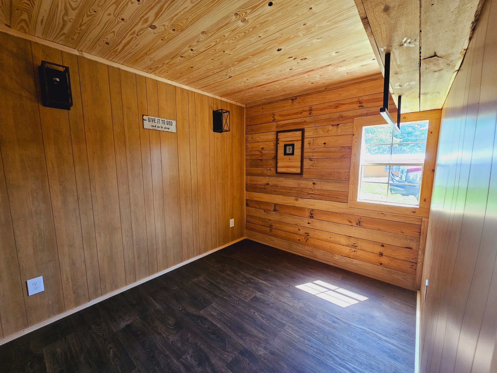 An empty room with wooden walls and a window.