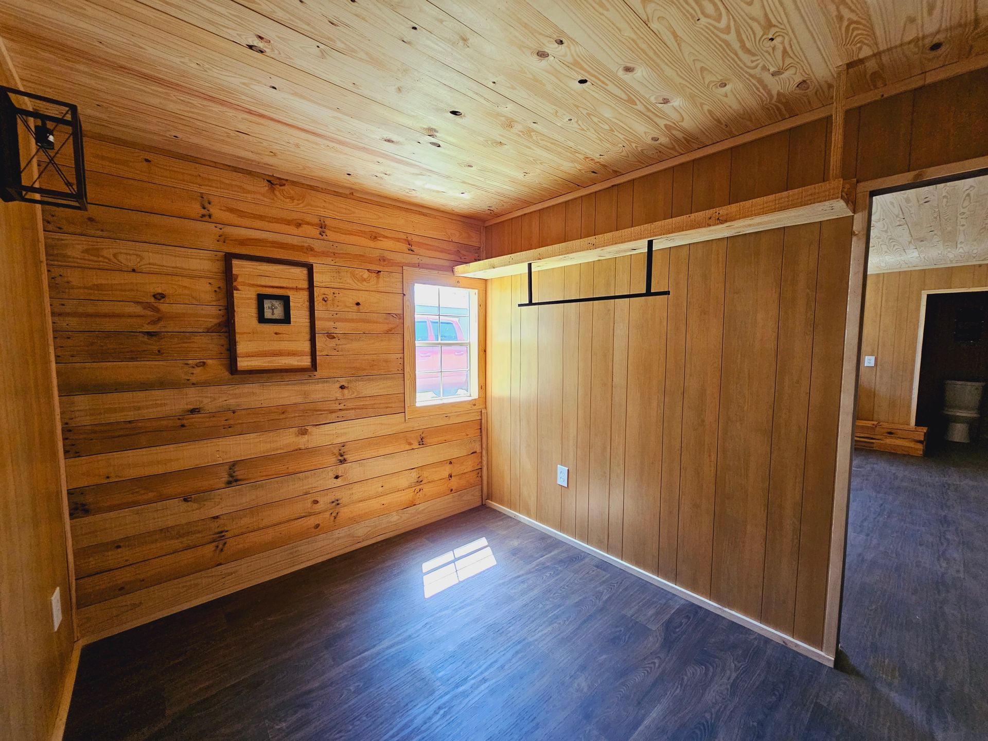 An empty room with wooden walls and a window.